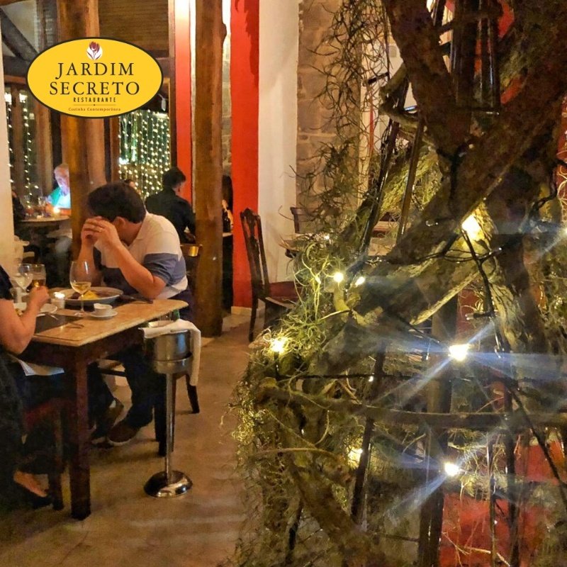 Clientes à mesa em uma noite no Restaurante Jardim Secreto