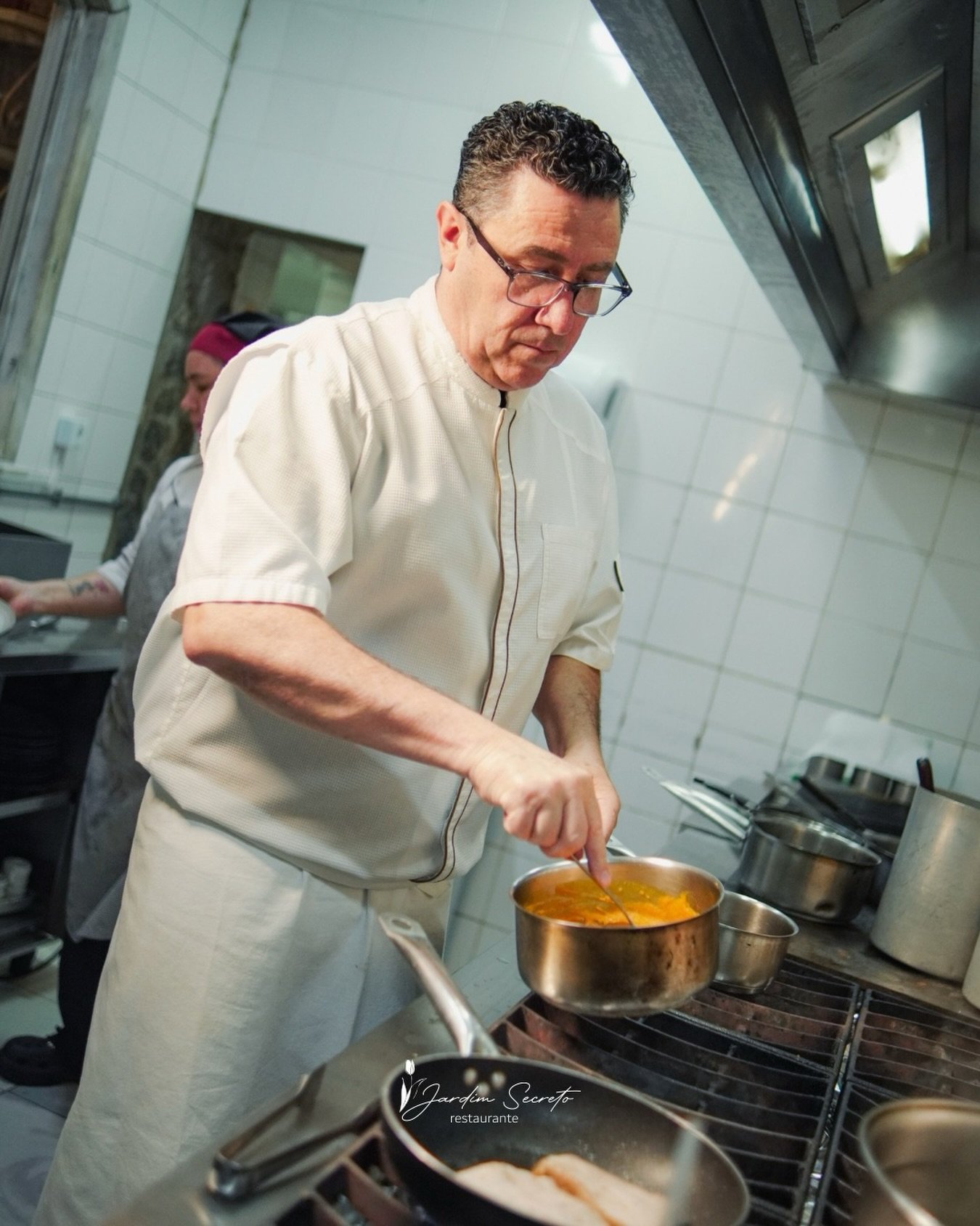 Chef Fabiano de Almeida preparando um prato na cozinha do Jardim Secreto