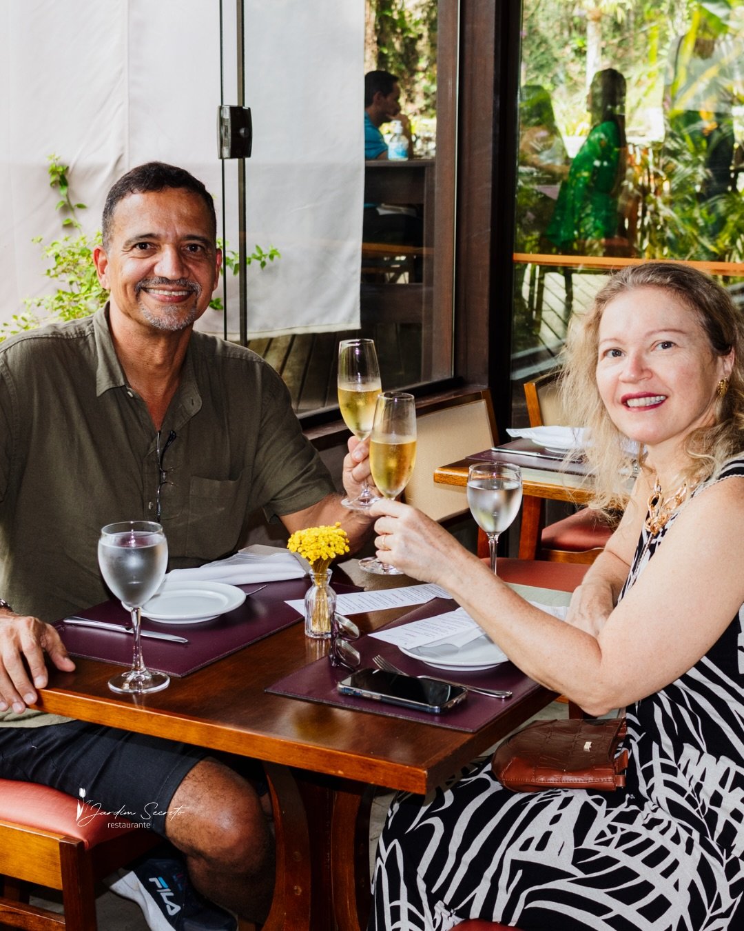Casal brindando à mesa no Jardim Secreto