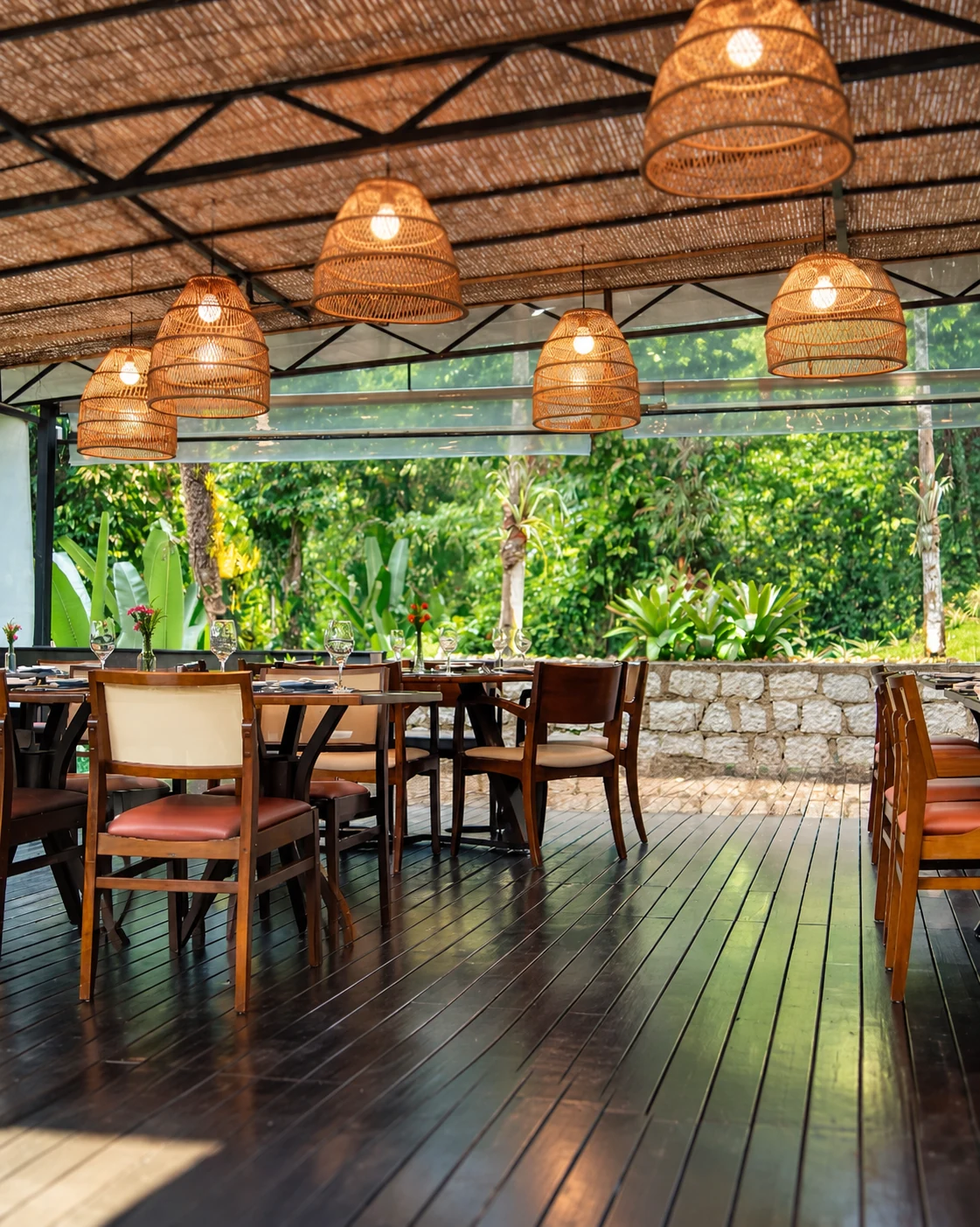 Varanda real do Restaurante Jardim Secreto, com mesas, luminárias e vista para as plantas do jardim